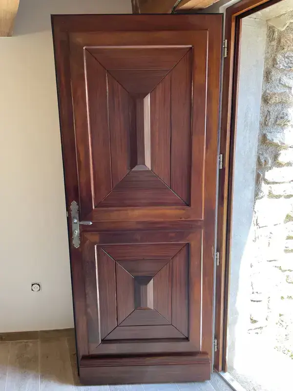 Porte en bois massif après lasure à Béziers — finition acajou chaud, boiserie restaurée